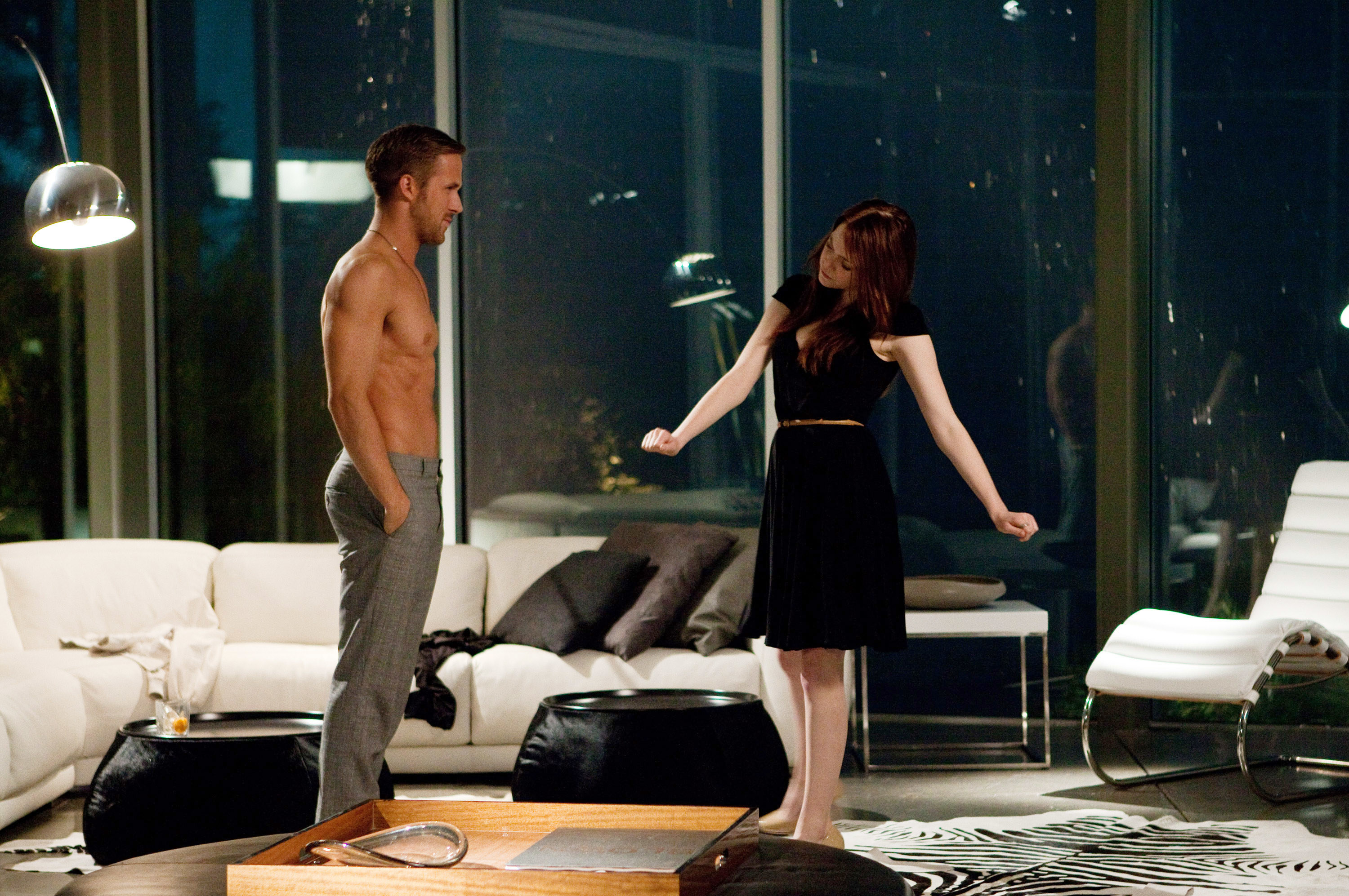 Ryan Gosling and Emma Stone facing each other in a lavish living room