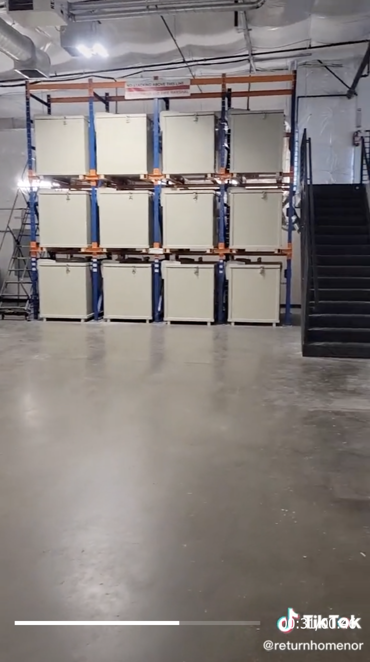 A warehouse with several large bins lined up against a wall