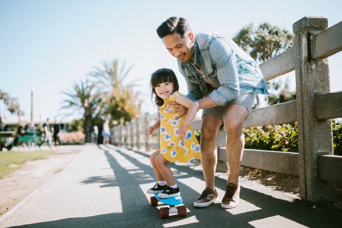 A dad helping his daughter learn how to skateboard