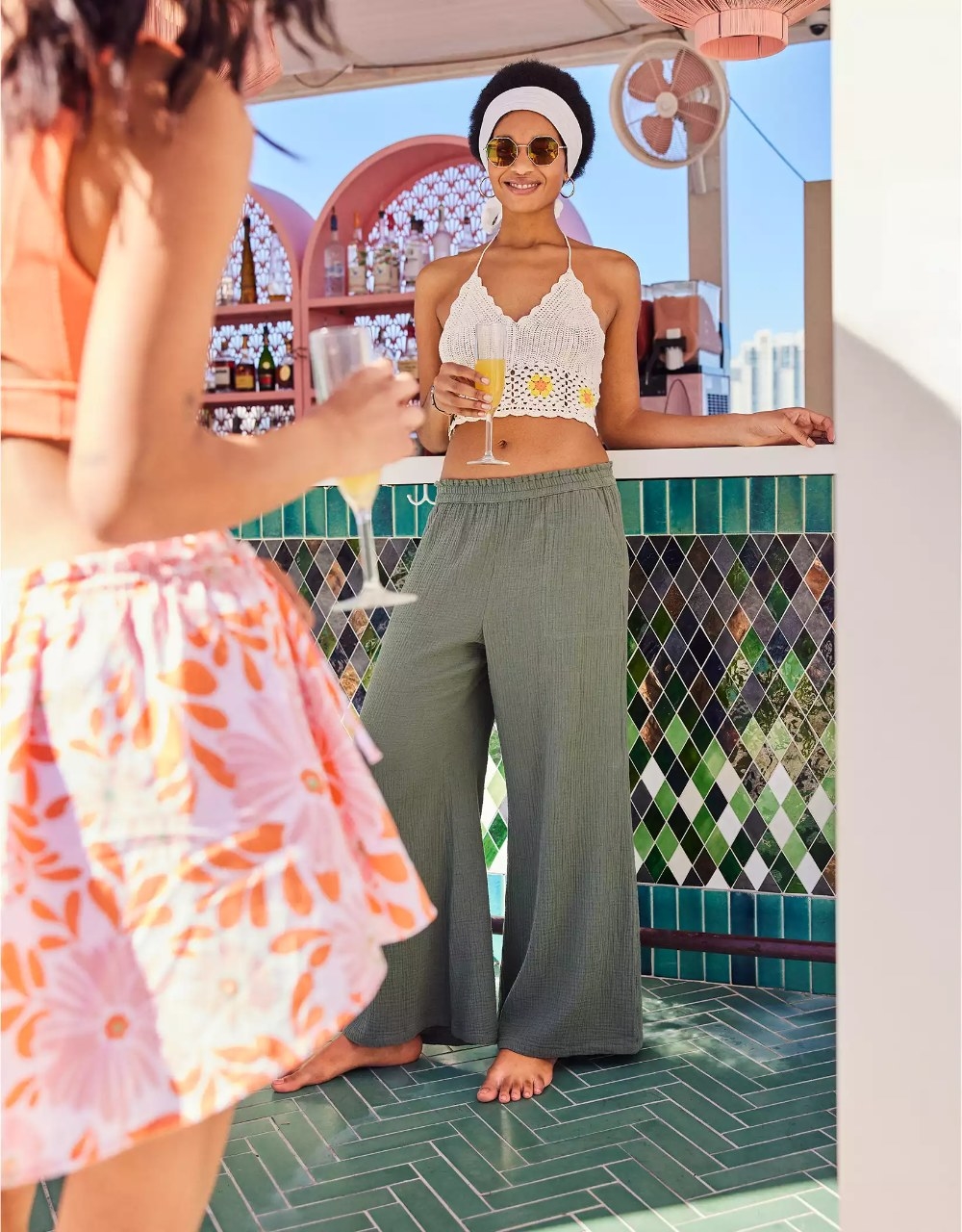 A model wearing the pants in the color Olive Fun, styled with a white crochet crop top