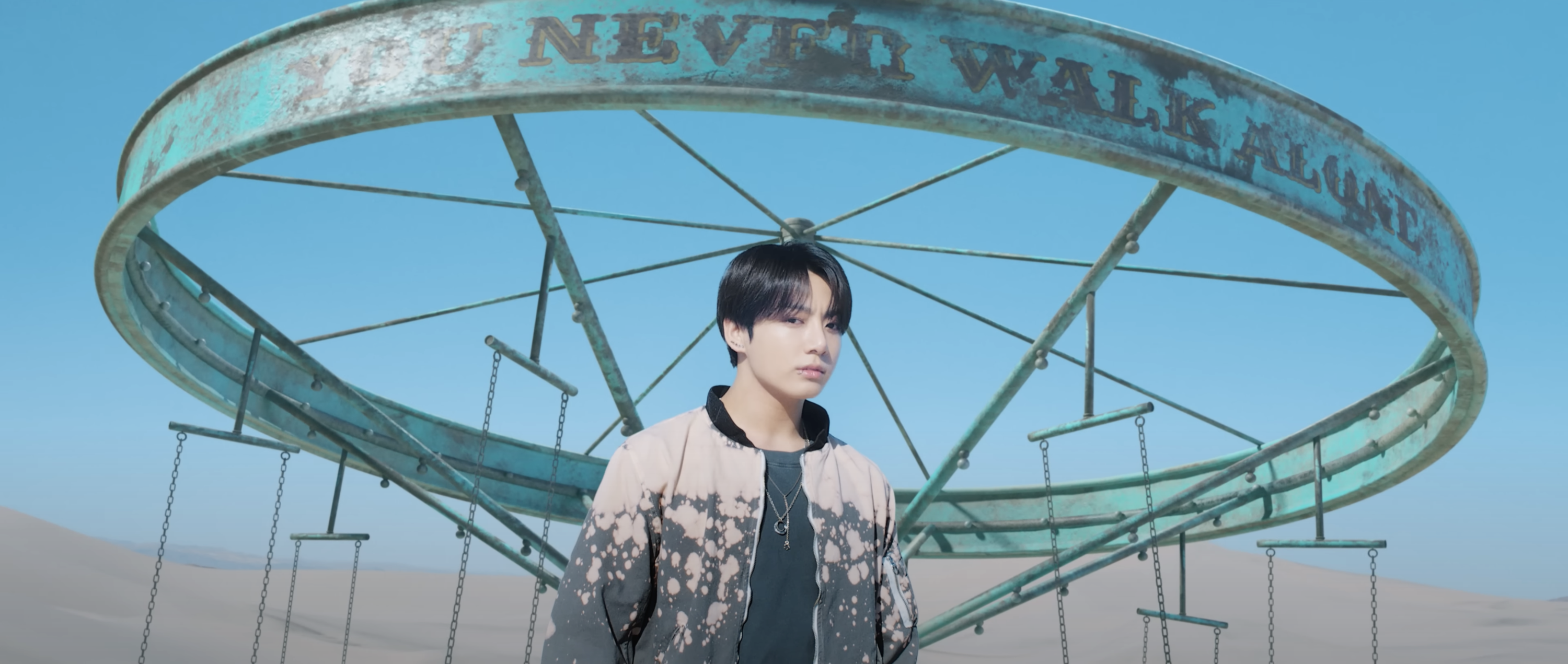 A member of BTA stands under a carousel with the words &quot;you never walk alone&quot; written on it