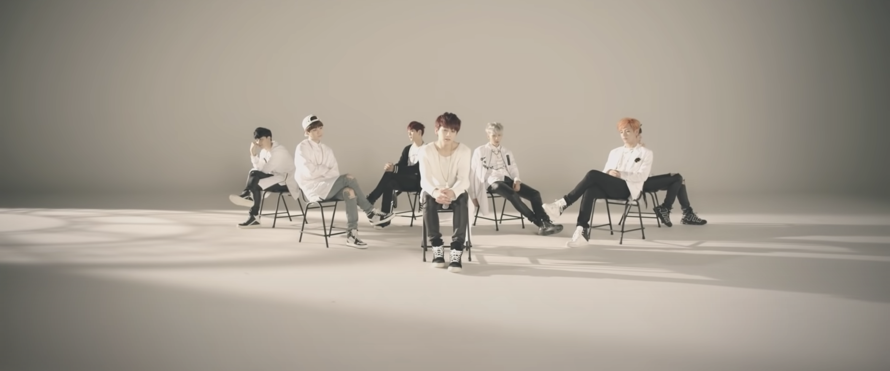 Members of BTS sit in a blank studio