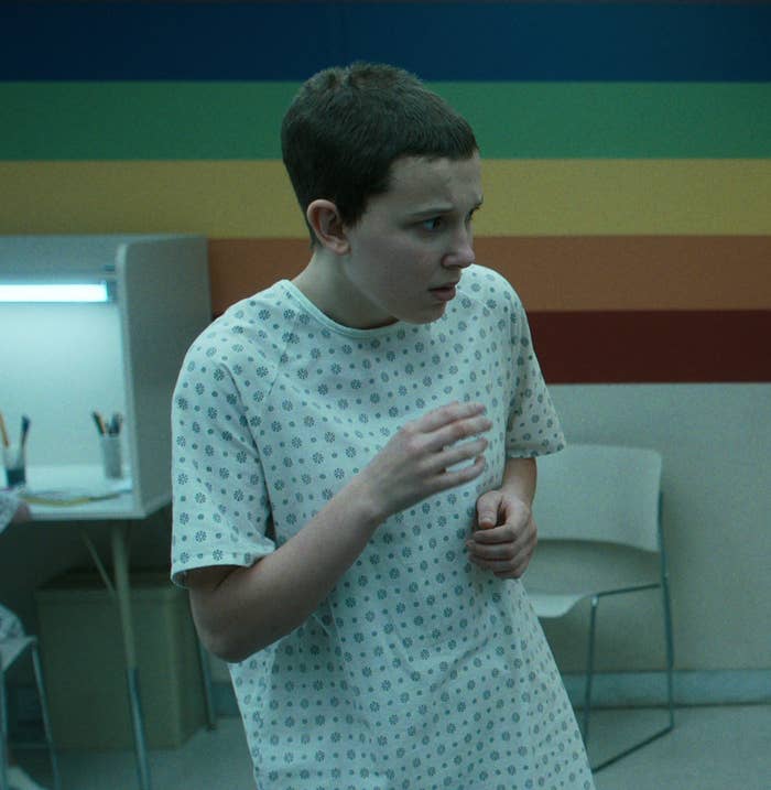 Millie as Eleven with hair shorn and wearing a hospital gown