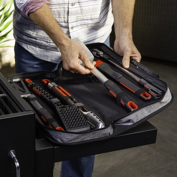 a model grabbing a spatula out of the carrying case with other black and silver tools