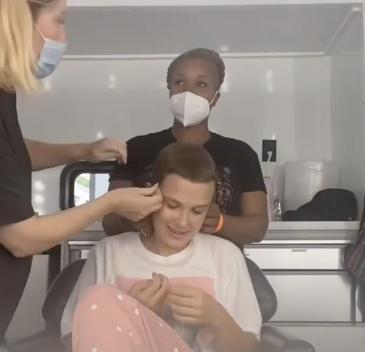 Millie smiling as stylists touch her hair