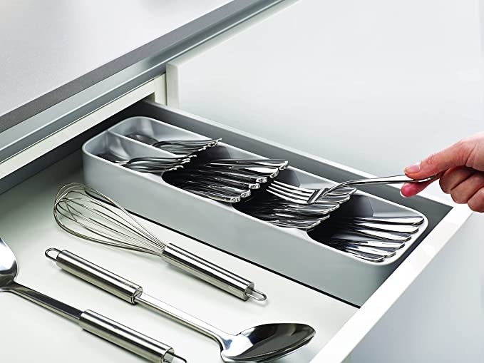 The organizer in a drawer with cutlery stored inside of it