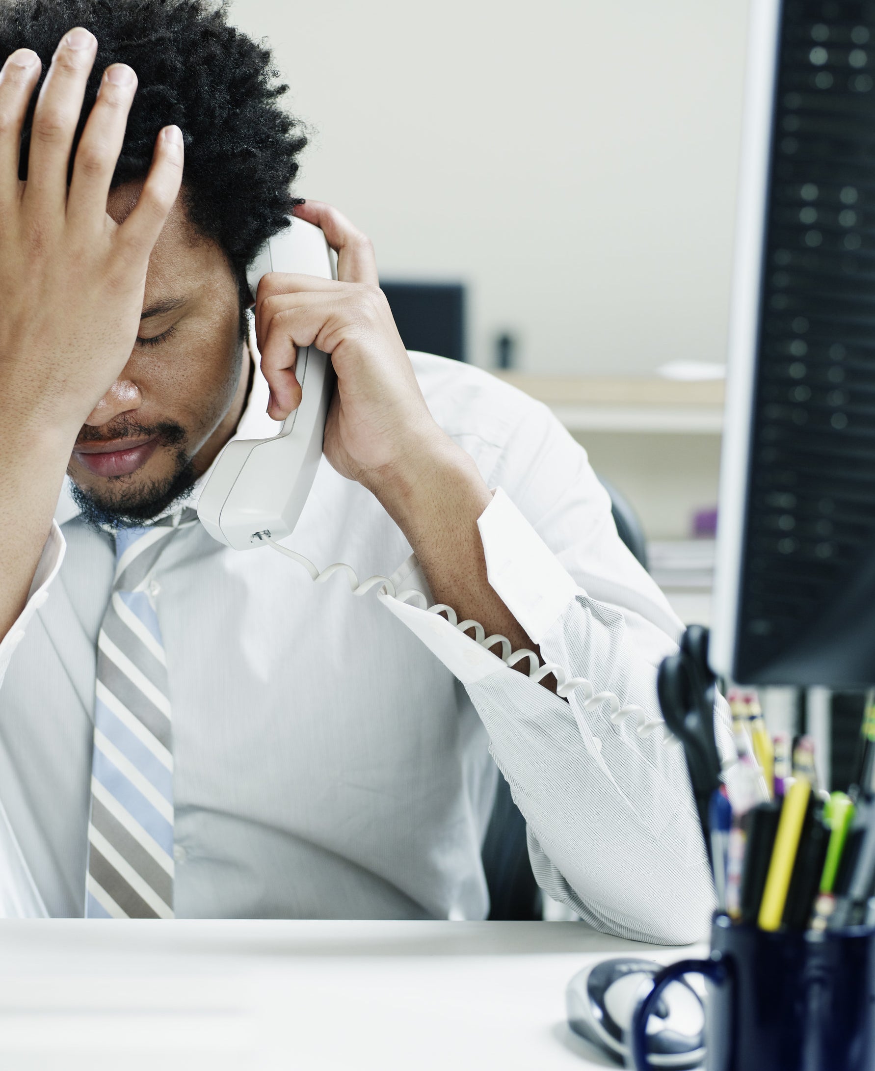 A man holds his hand to his forehead in frustration during an emotional phone call