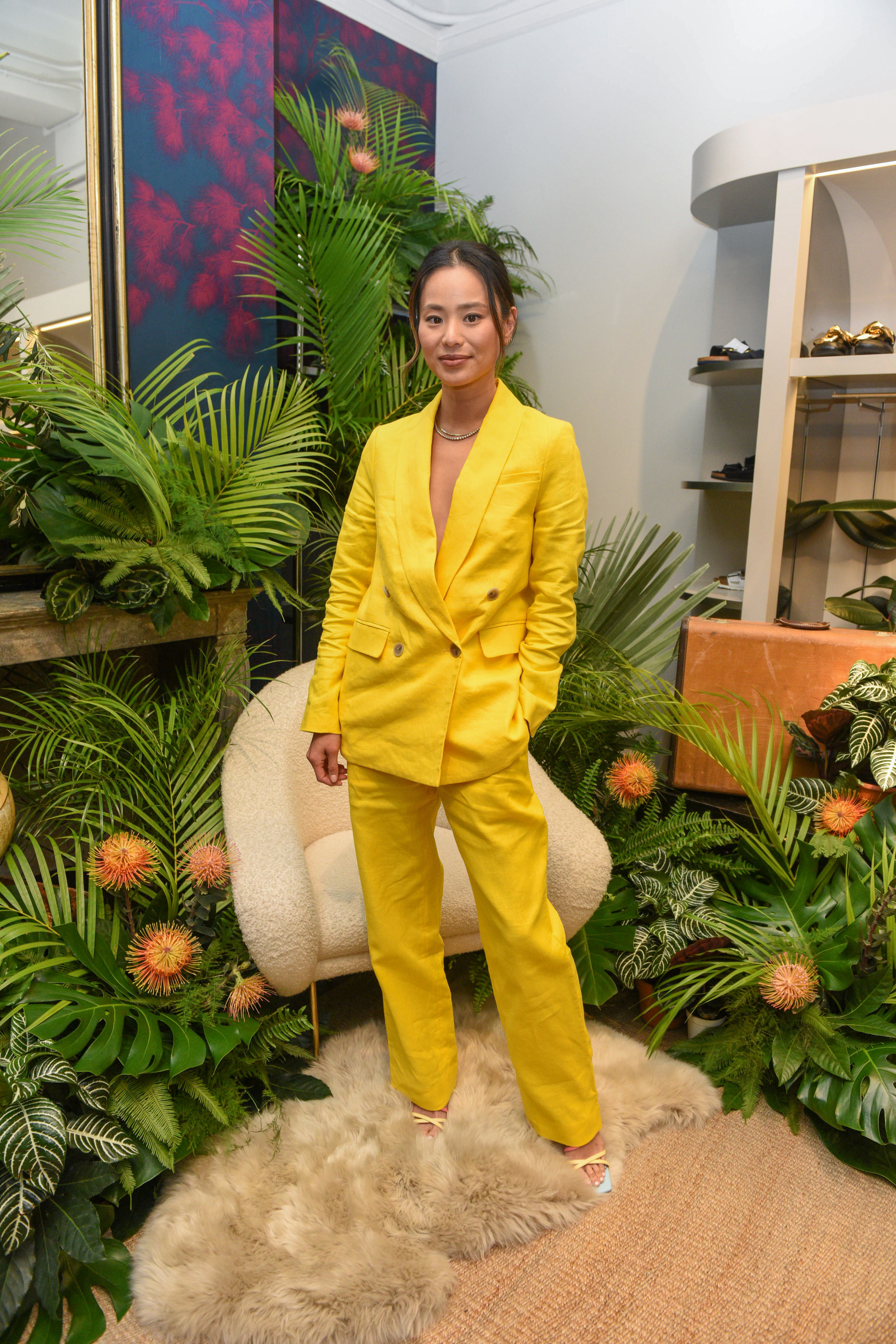 Jamie posing on front of a foliage display and a chair