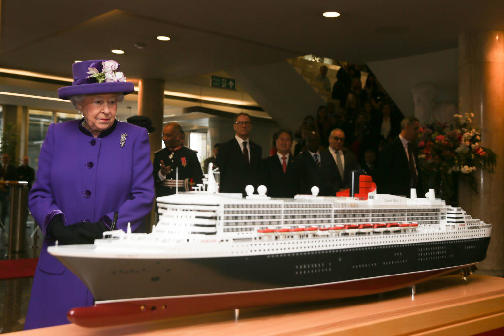 Queen Elizabeth II standing by a model ship