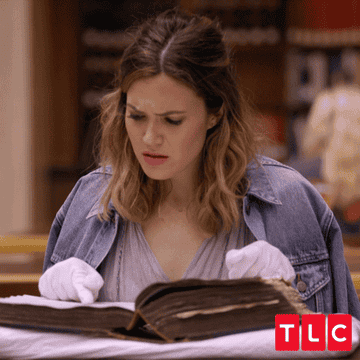 GIF of a Mandy Moore reading a book and shrugging in confusion