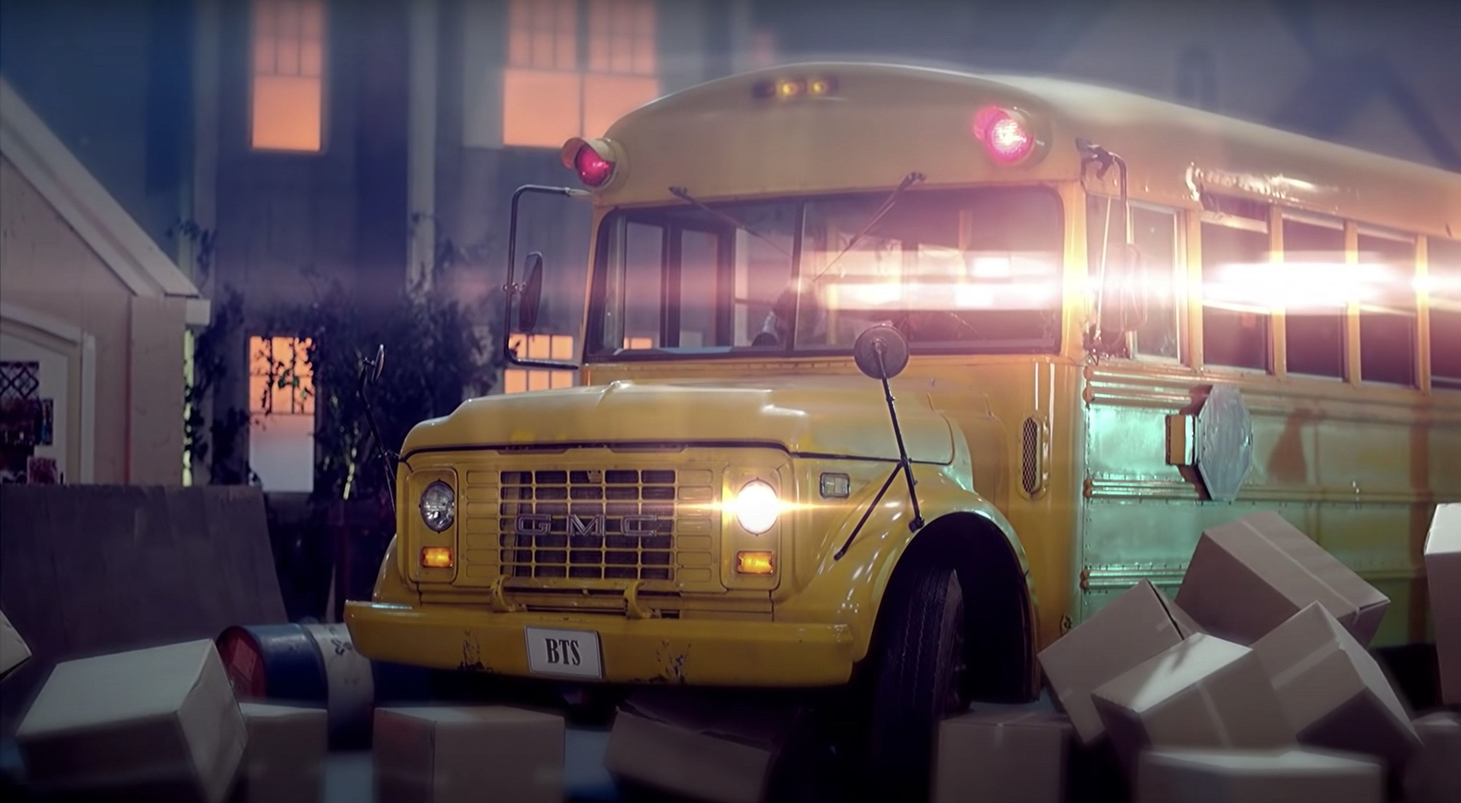 A still from a music video shows a school bus with the license plate &quot;BTS&quot;