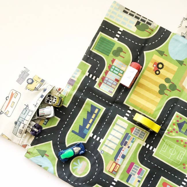 The car mat with attached pouch and a few toy cars