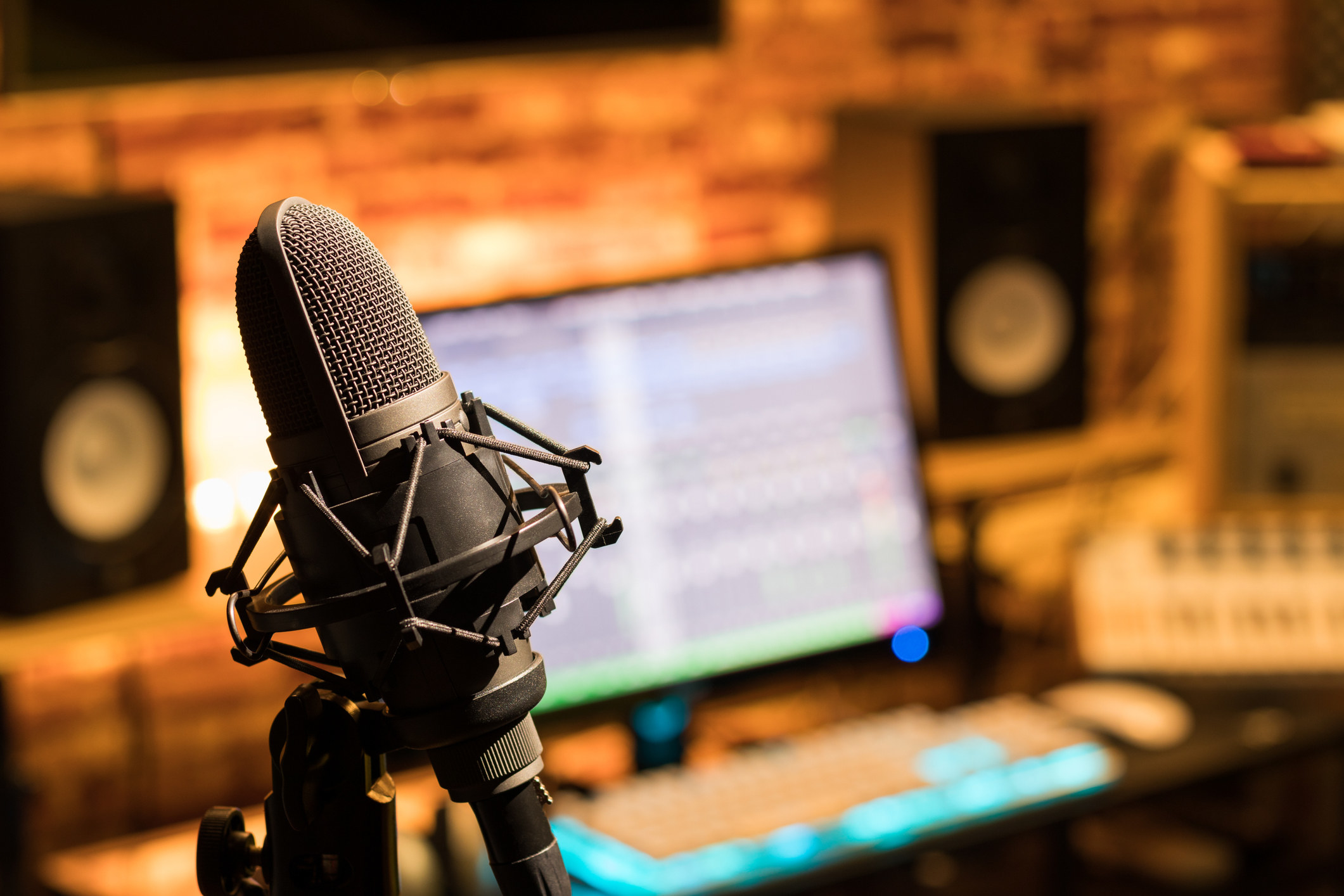 A microphone set up in a booth; there is also a laptop and speakers set up