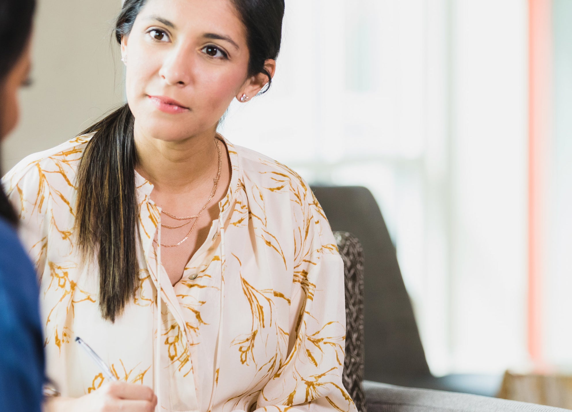 A woman takes notes during an interview with a visiting client