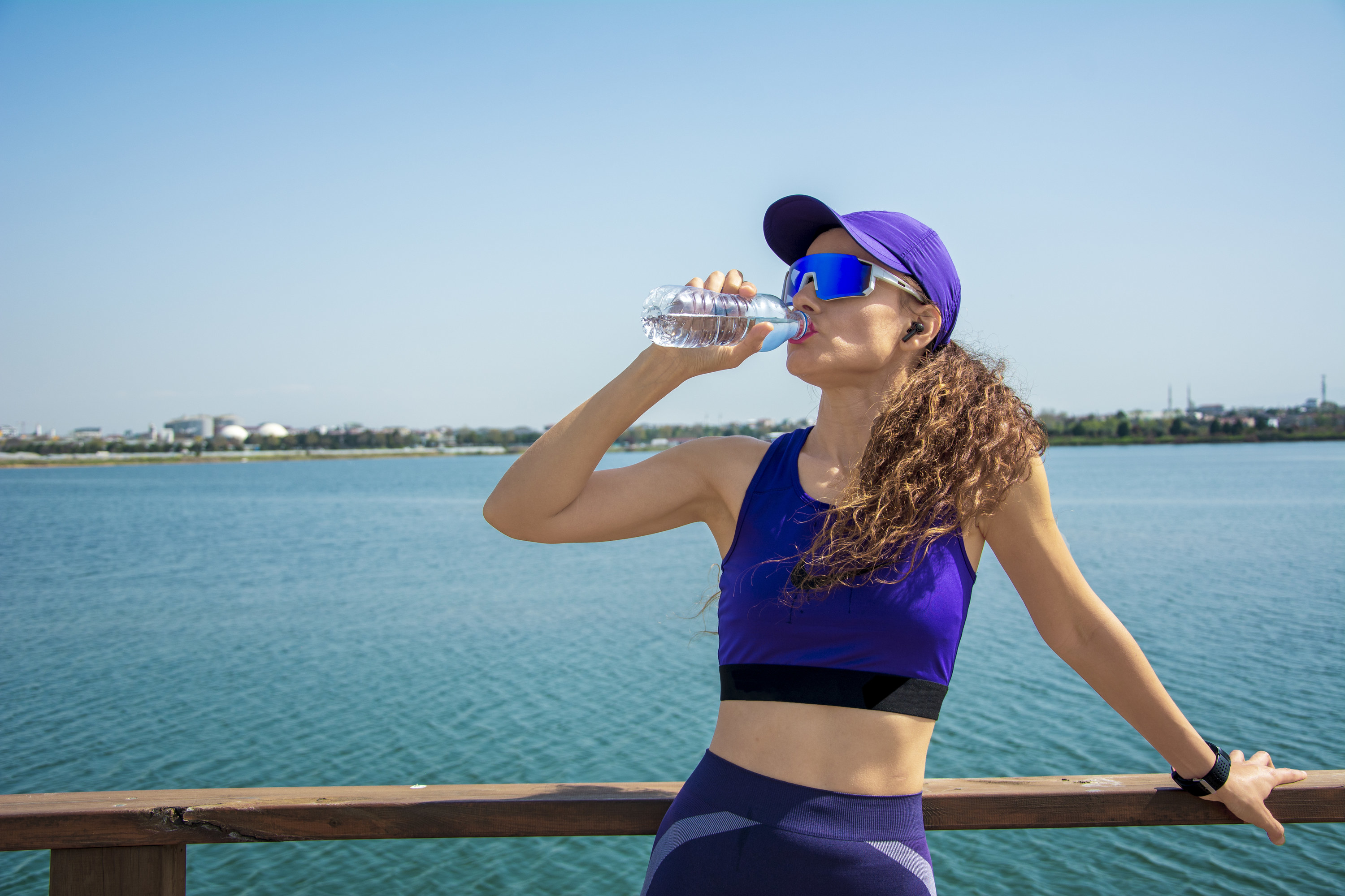 An athlete woman drinking water by the river