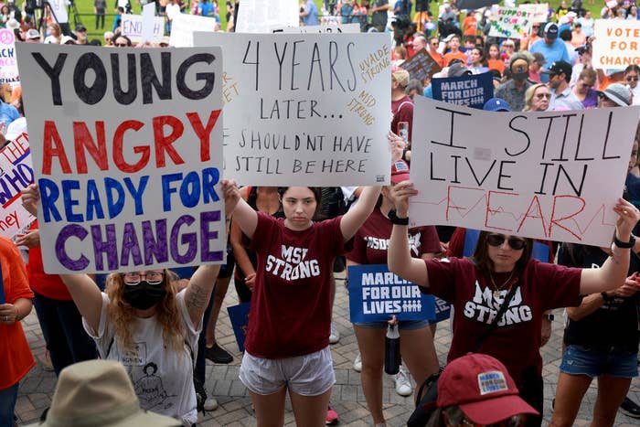 Young people holding up signs, including &quot;I still live in fear&quot; and &quot;Young, angry, ready for change&quot;