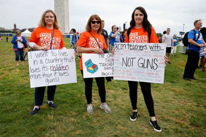 Protesters hold signs including "I want to live in a country loves its children more than it loves guns!"