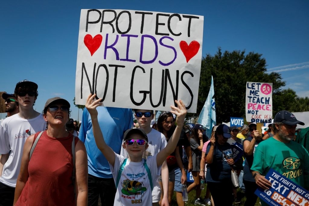 Young people holding signs, including &quot;Protect kids, not guns&quot;