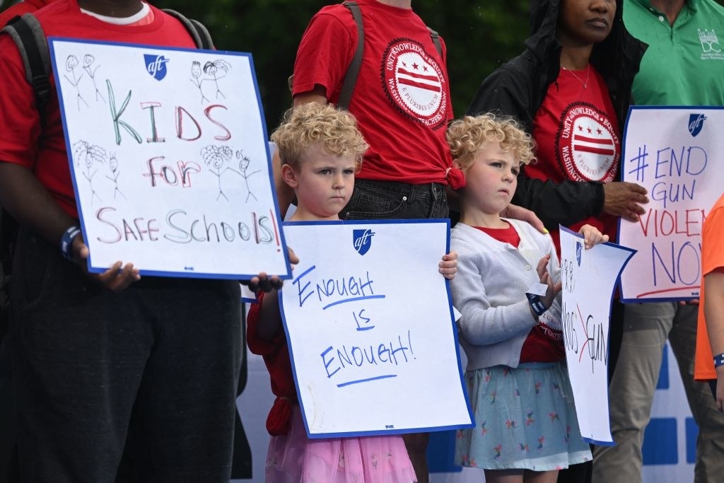 Children holding signs, including &quot;Enough is enough!&quot; and &quot;Kids for safe schools!&quot;