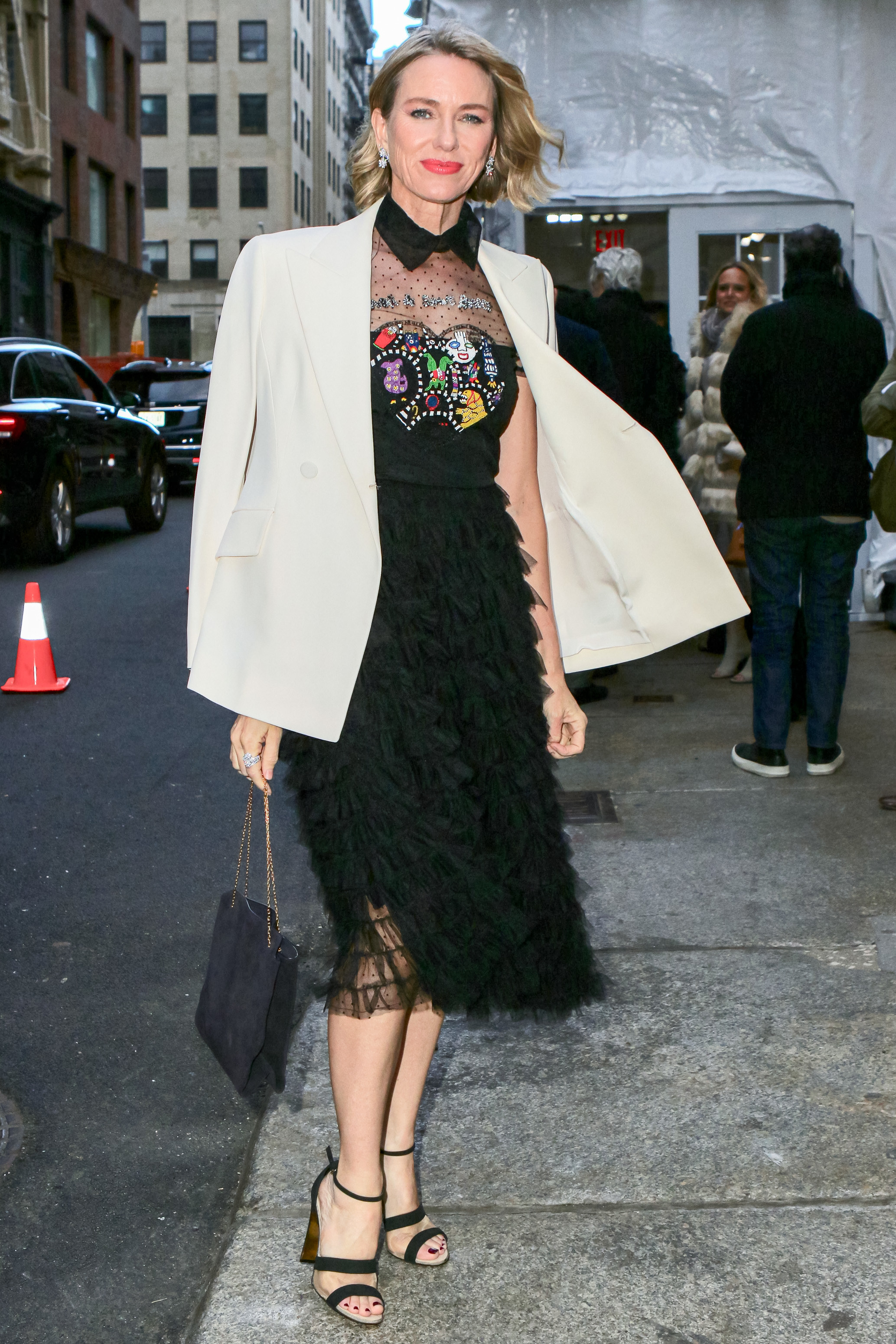Naomi posing in a dress and blazer on the sidewalk