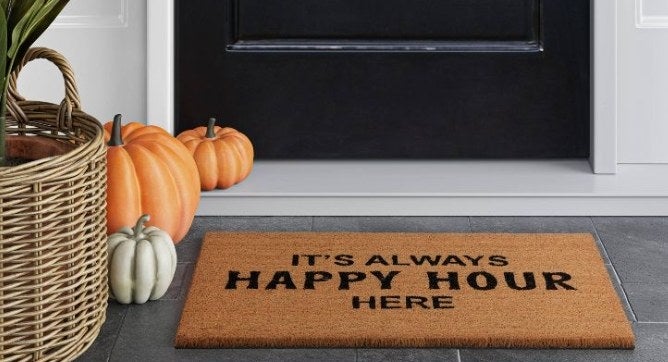 A brown doormat that reads &quot;It&#x27;s Always Happy Hour Here&#x27;