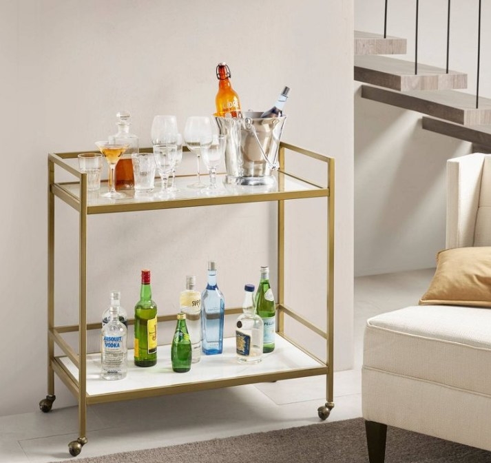 Gold Martha Stewart bar cart with glasses and drinks sitting on both shelves