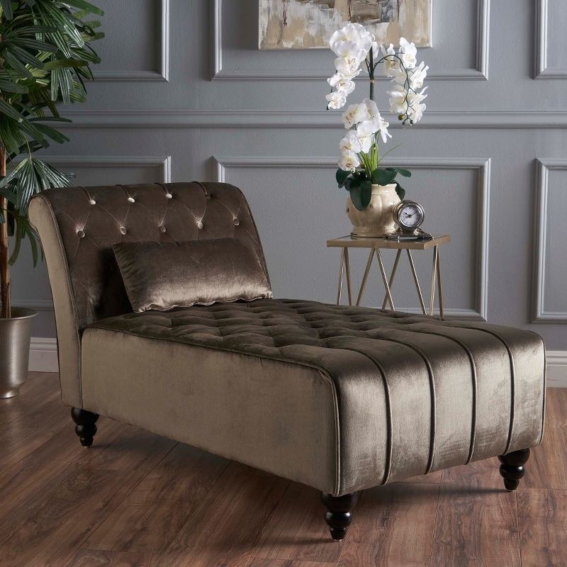 a gray velvet chaise in a living room next to flowers