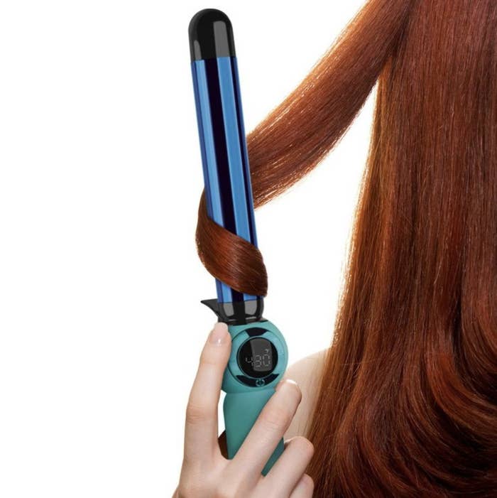 A person styling their hair with a heat-styling tool