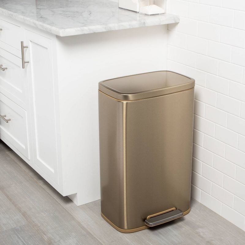 The trash can in a kitchen in the gold color