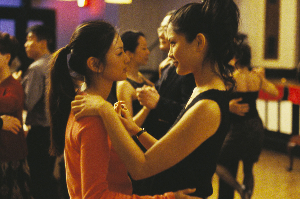 two women dance together and stare at one another in a dance hall