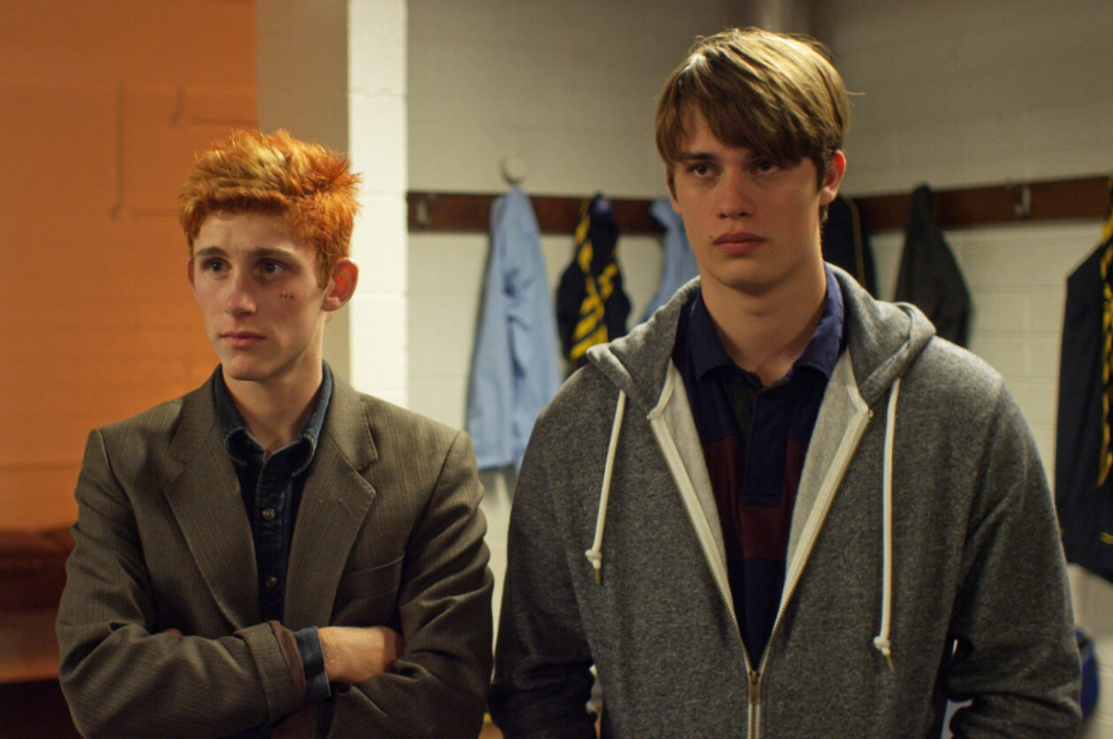 two young men stand next to each other in a changing room but they are fully clothed and they look cross