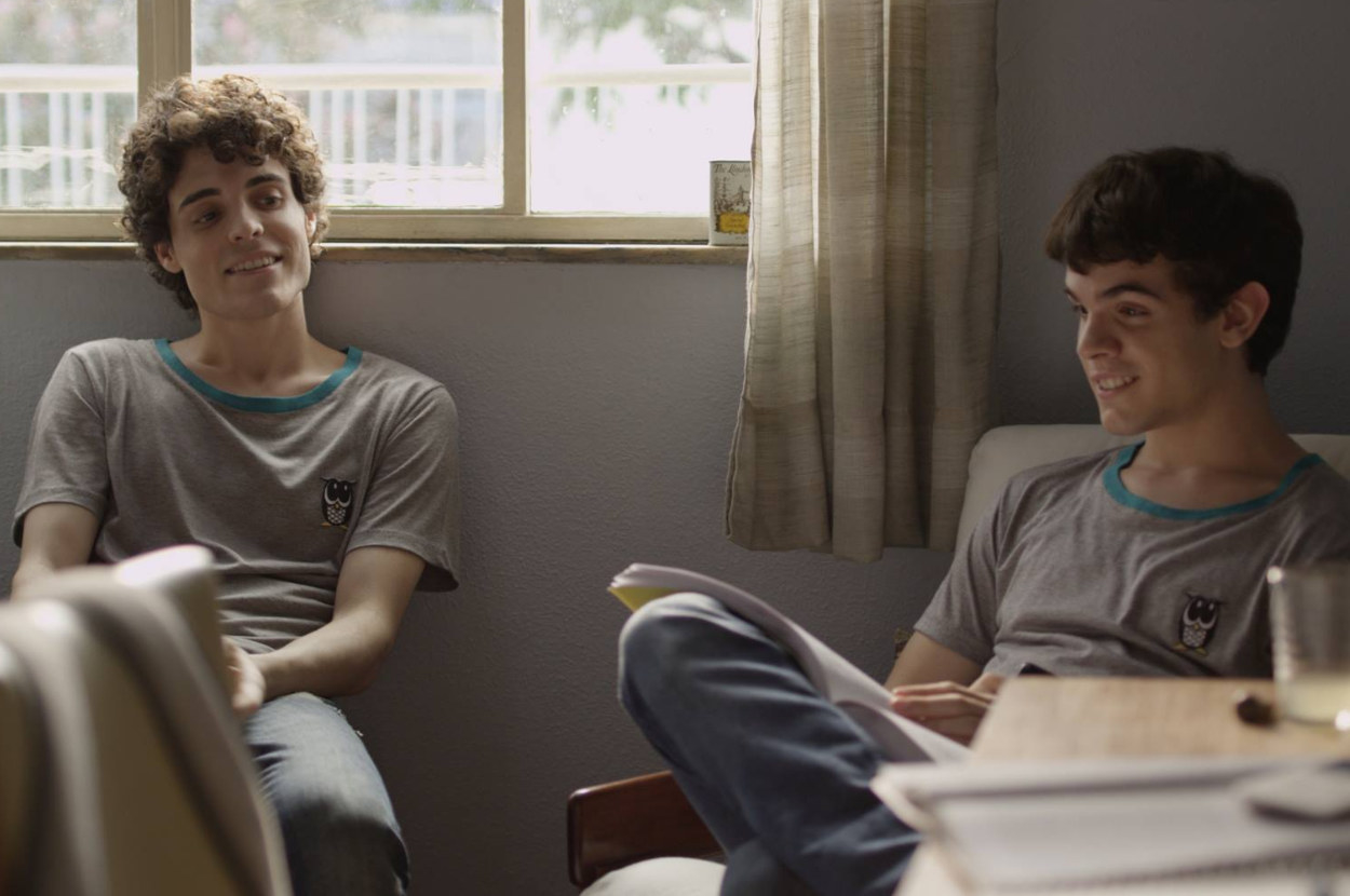 两个男孩坐在一间卧室在一起看着另一个但他是盲目的,直视前方