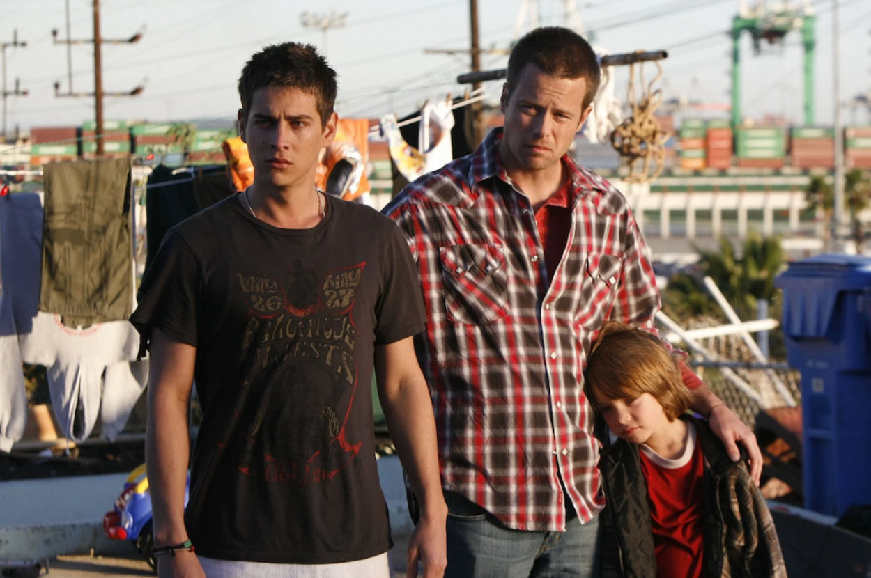 two men and a young boy stand on a roof garden surrounded by urban area