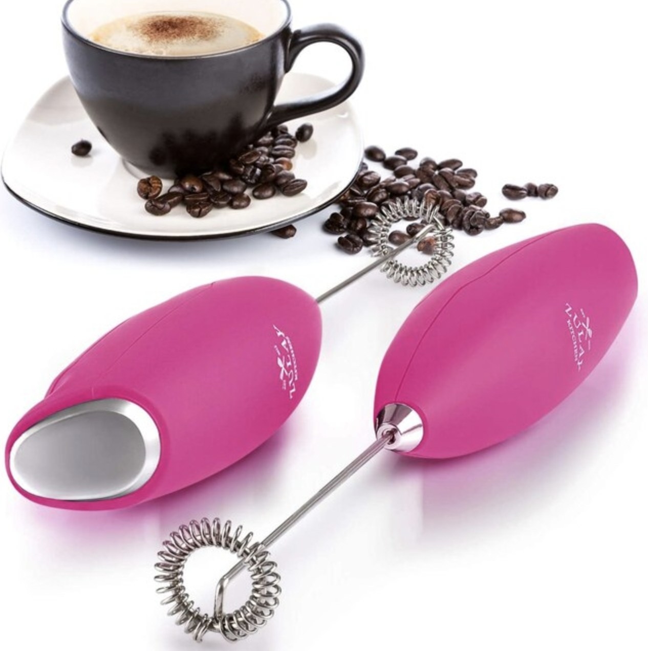 The pink frother next to latte with coffee beans spread out on table
