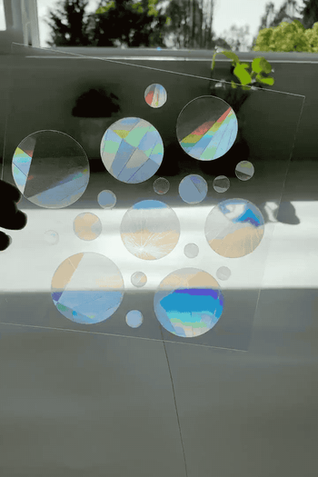a gif of a sheet of the circle stickers being put in the sun and rainbows streaming through