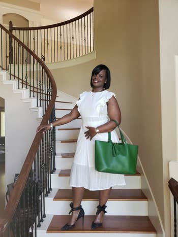 Reviewer is wearing the white dress with a green bag