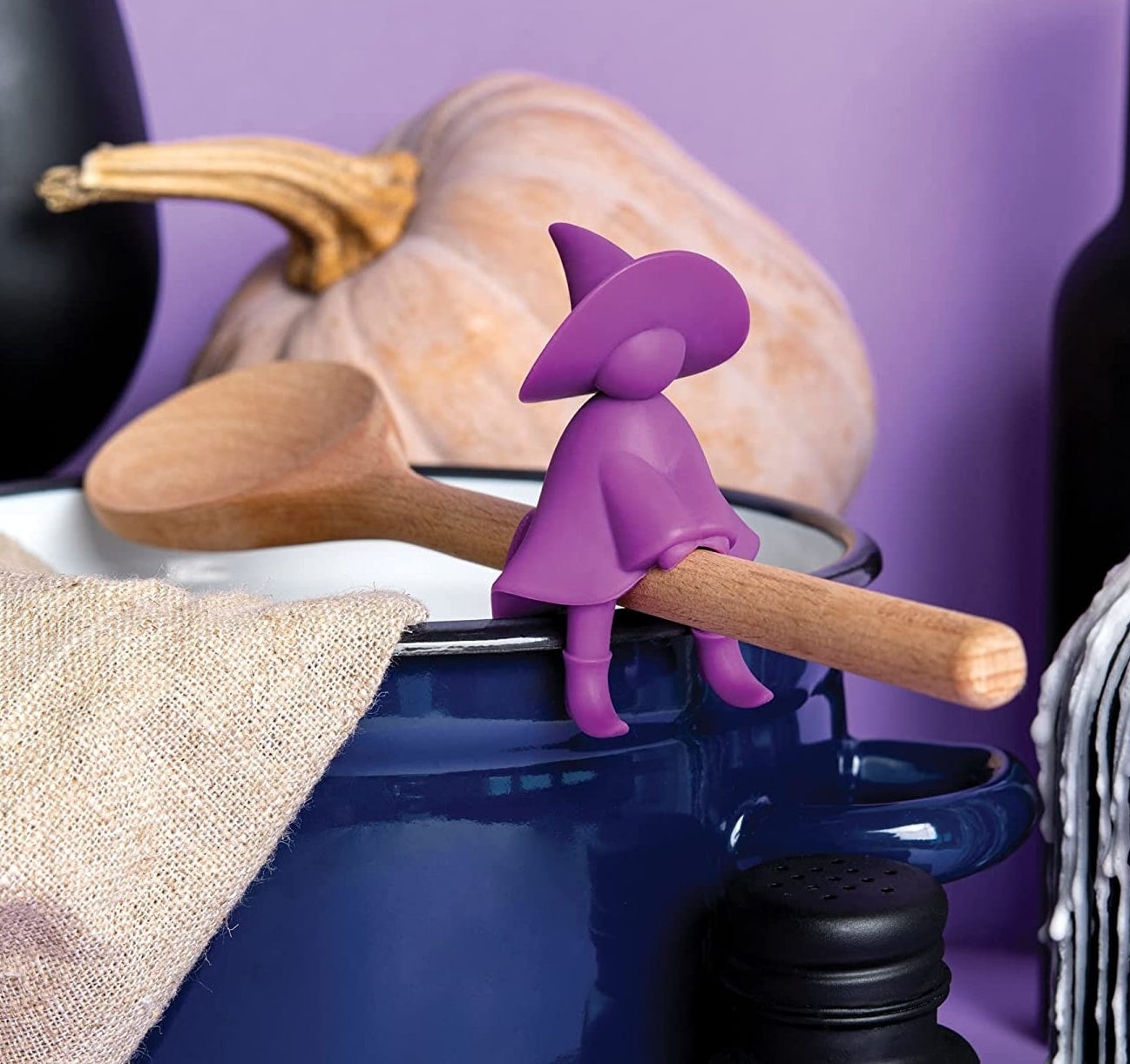 a silicone steam spoon rest shaped like a witch clipped to the edge of a pot