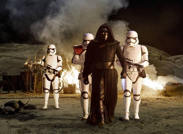 A man dressed in sith robes is surrounded by armored guards