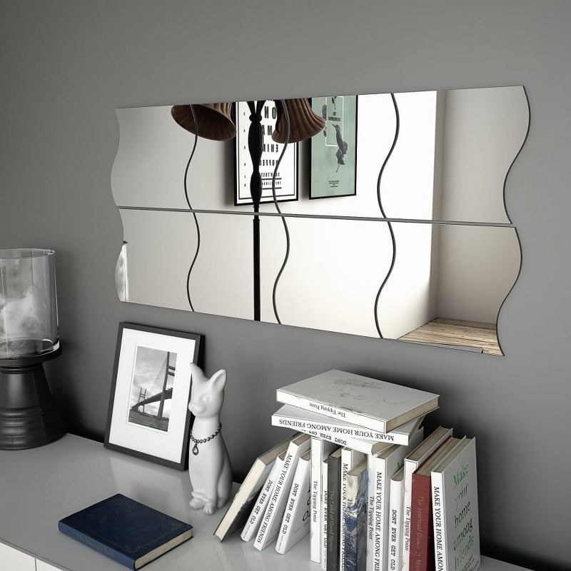 Eight-piece mirror set mounted on gray wall above shelf with books, framed art, and other accessories