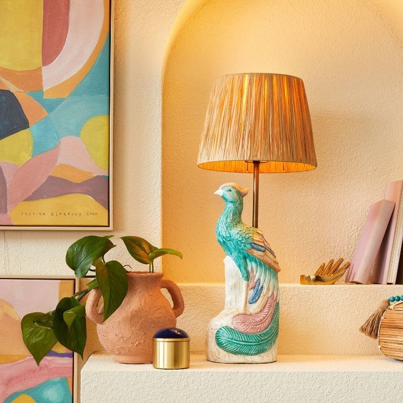 Lamp on stucco shelf surrounded by pottery, a plant, and other decor