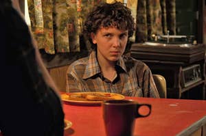 Eleven from Stranger Thing sitting in front of a plate with French toast on it