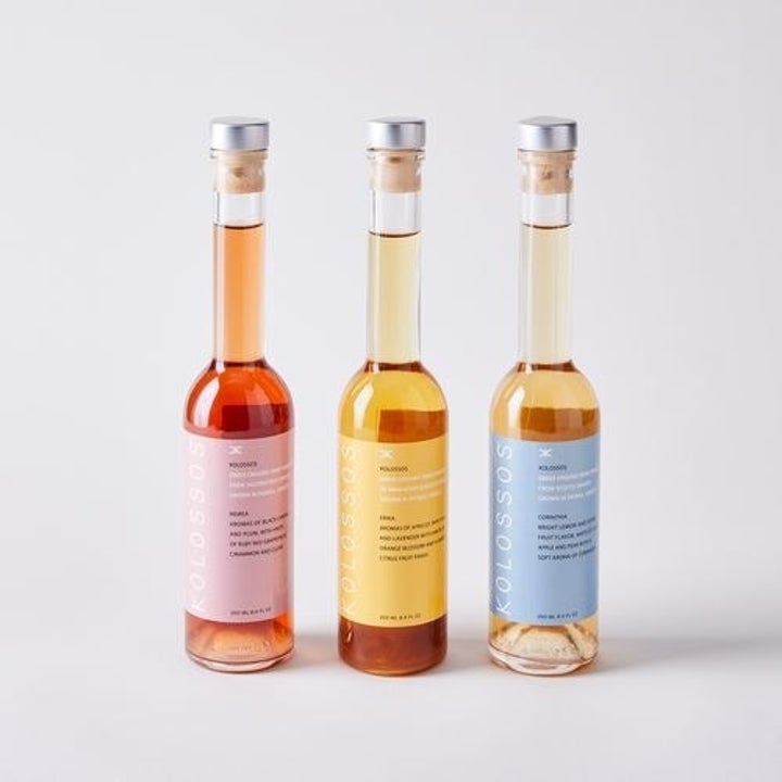 three wine vinegar bottles in pink, yellow, and blue labels