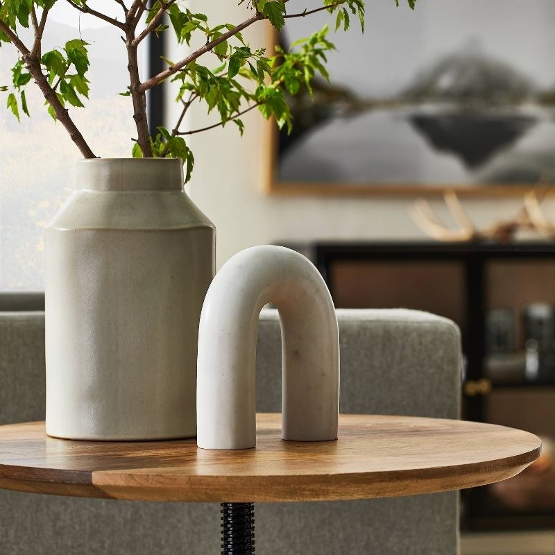Arched decor placed on top of circular wooden table in living room