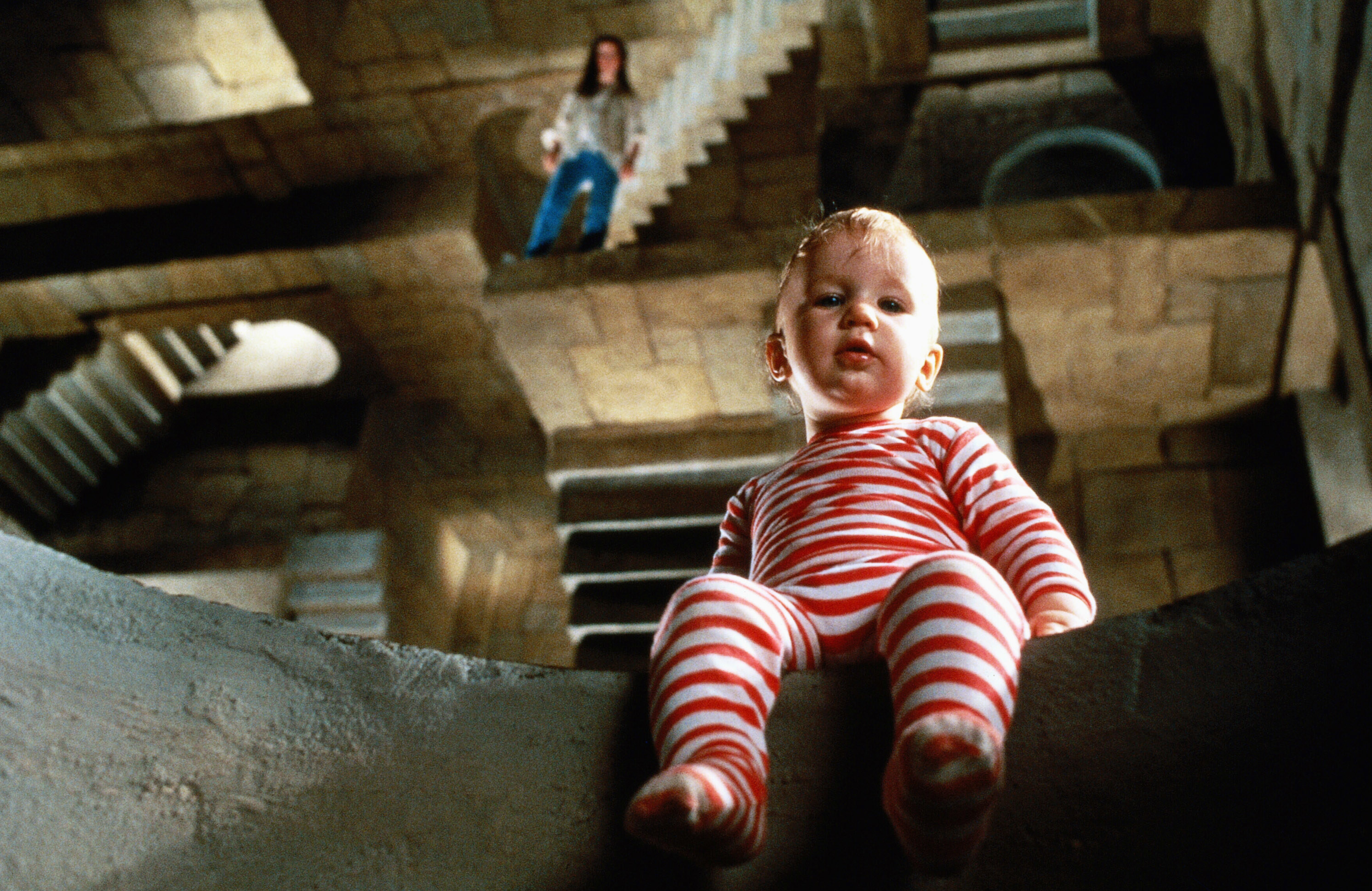A baby sits on a ledge in a maze