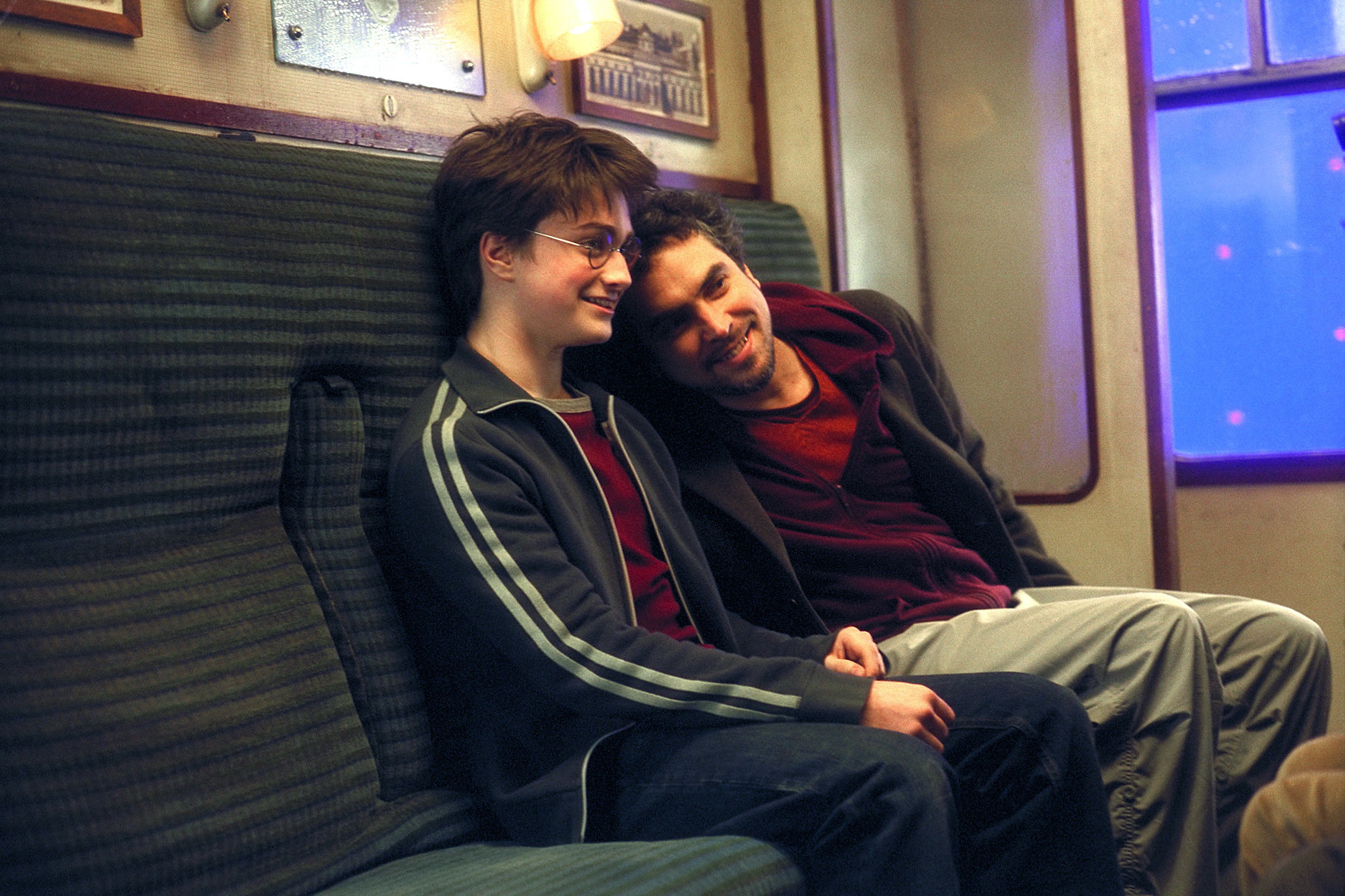 Daniel Radcliffe and Alfonso Cuarón sitting on the Hogwarts Express