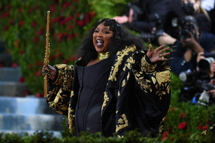 Lizzo holding a flute as she smiles on the steps of the Met Gala