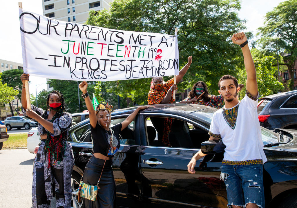 protestors hold signs in support of juneteenth and black lives