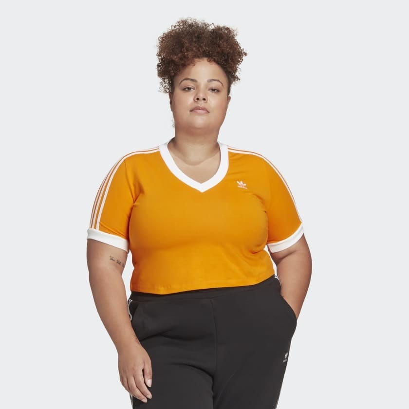 a model wearing the orange cropped tee with three white stripes on the sleeves