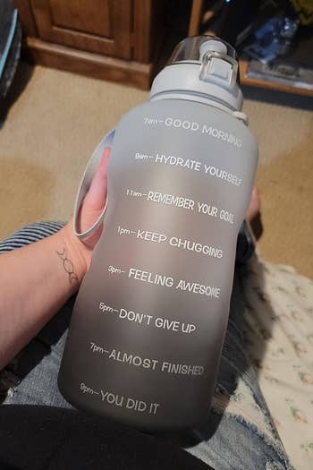 reviewer holding the bottle in black and grey