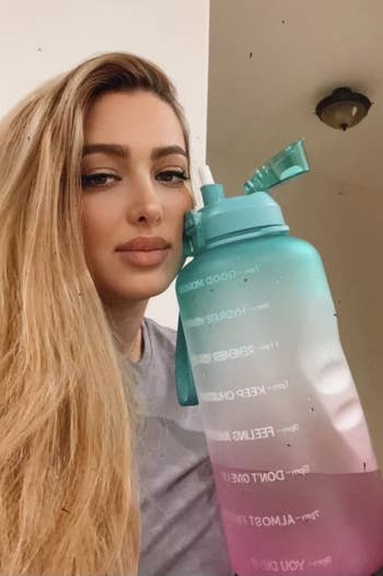 reviewer holding the water bottle next to their face, showing how big it is